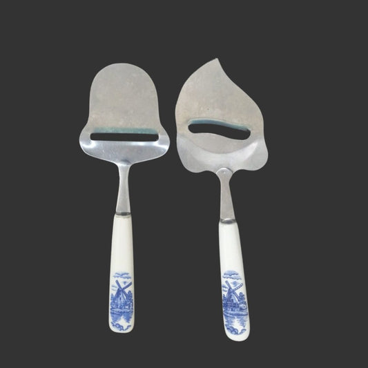 Two metal cheese graters with decorative white handles featuring blue patterns on a black background.